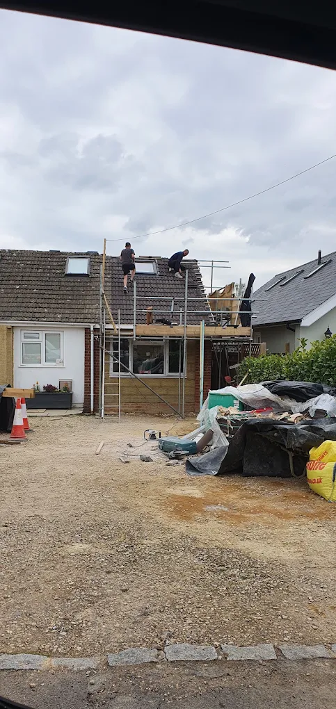 Scaffolded bungalow being re-roofed alongside a new extension
