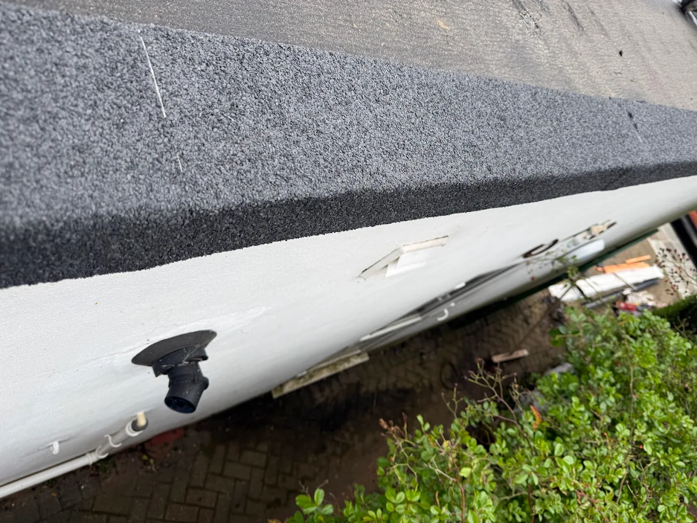 Close-up of a flat roof edge with a new white drip trim and outlet