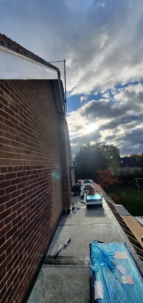 Flat roof running along a narrow side return between two brick houses
