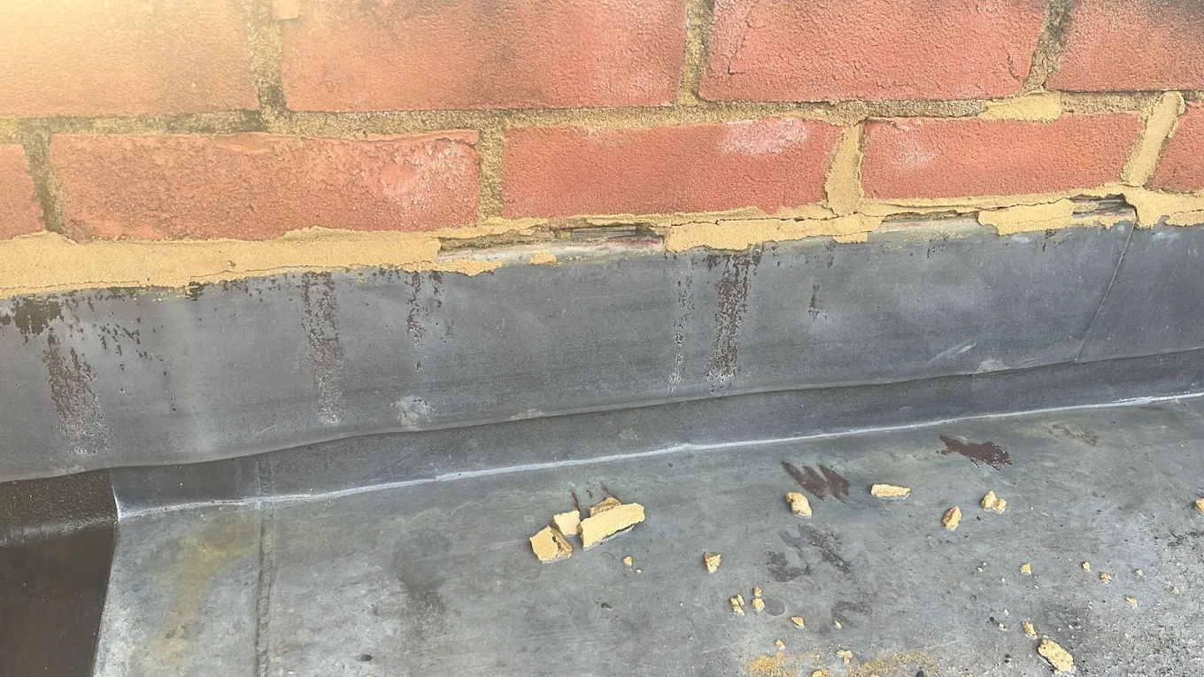 Lead flashing chased and dressed into brickwork above a flat roof