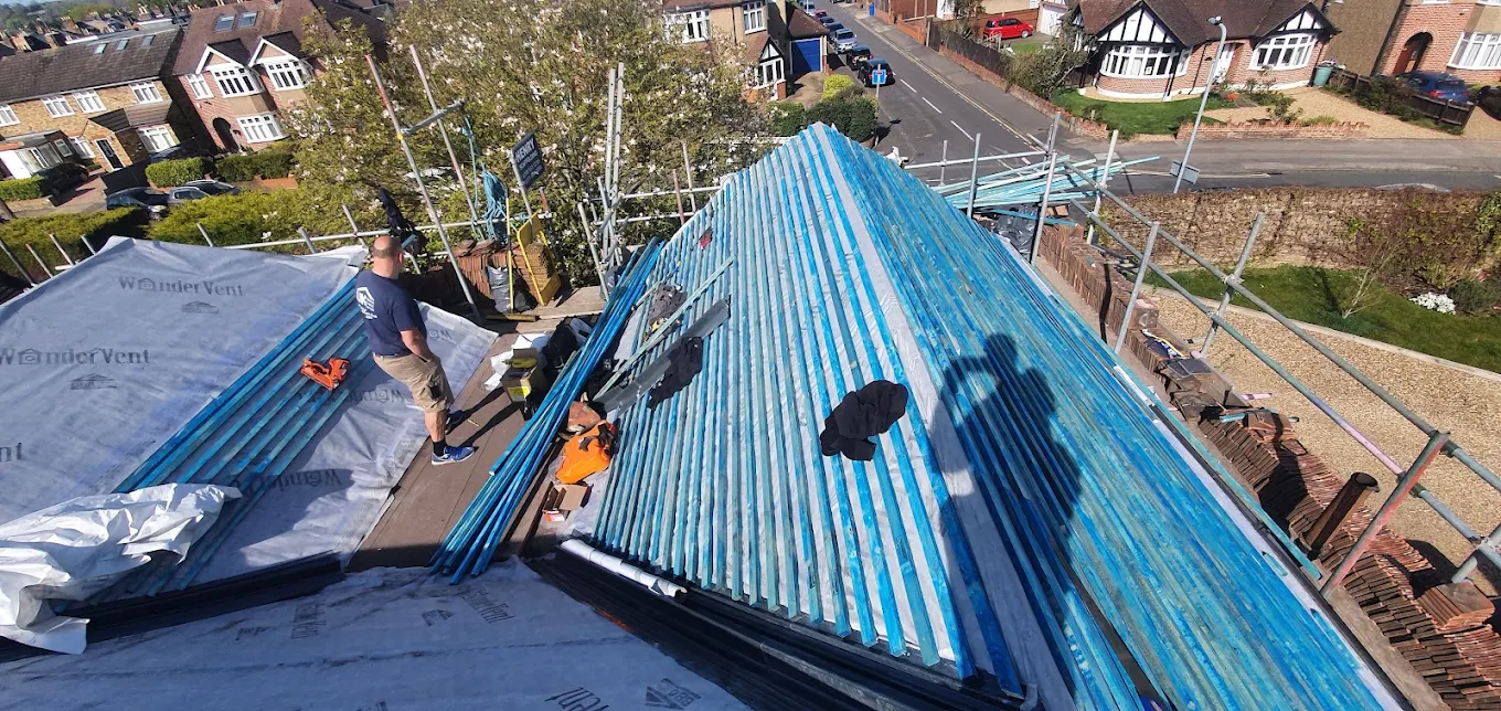 Roof stripped back and battened out ready for tiling, roofers working on the scaffold