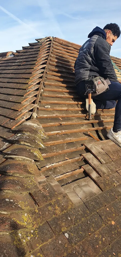 Roofer stripping old tiles off a pitched roof to reach the battens
