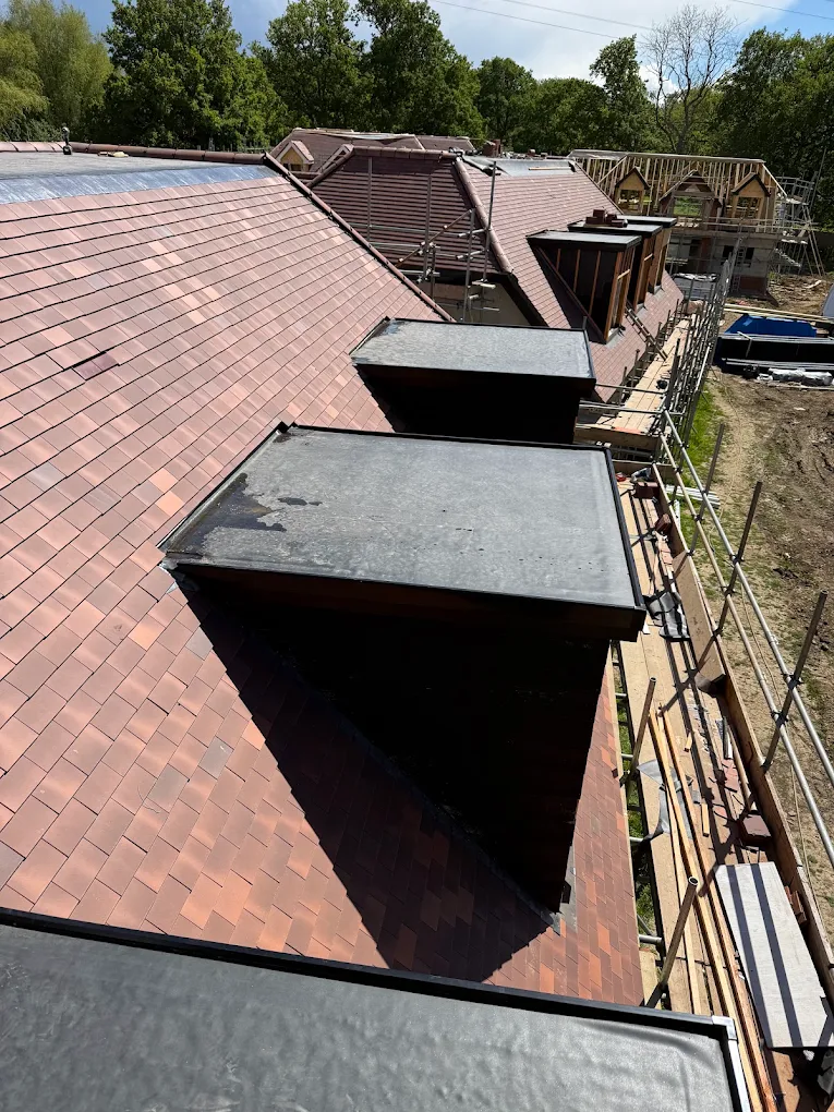 Finished clay tiled roof with flat-topped dormers and lead cheeks